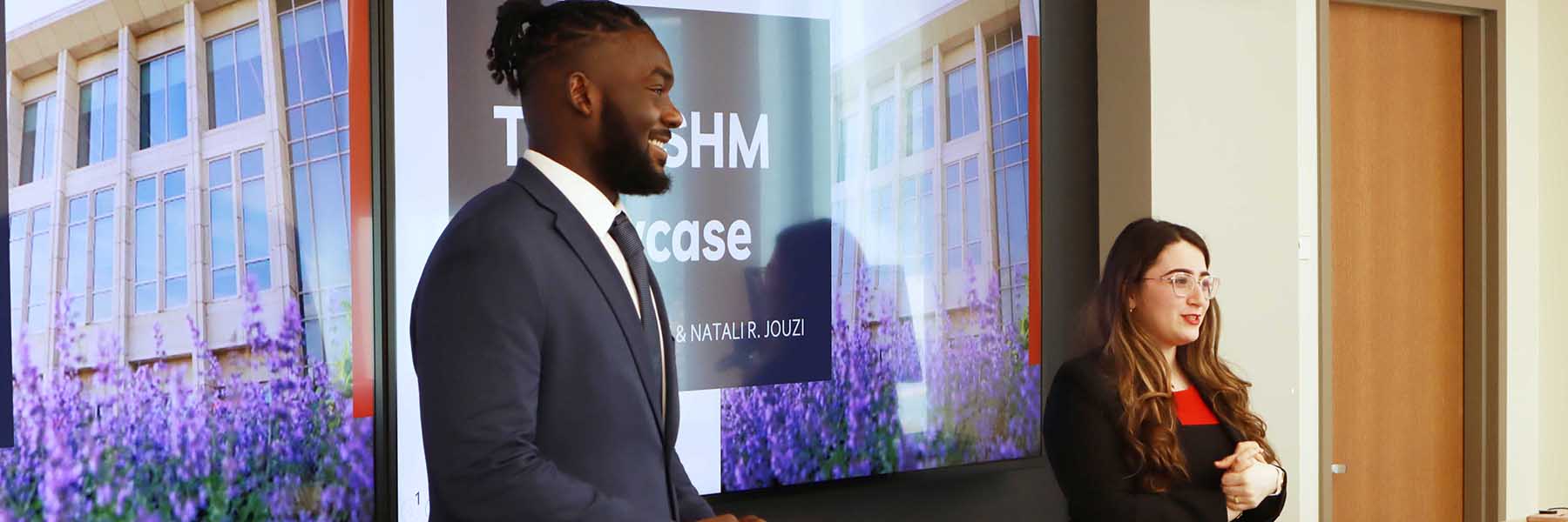 Two students in professional attire make a presentation. 